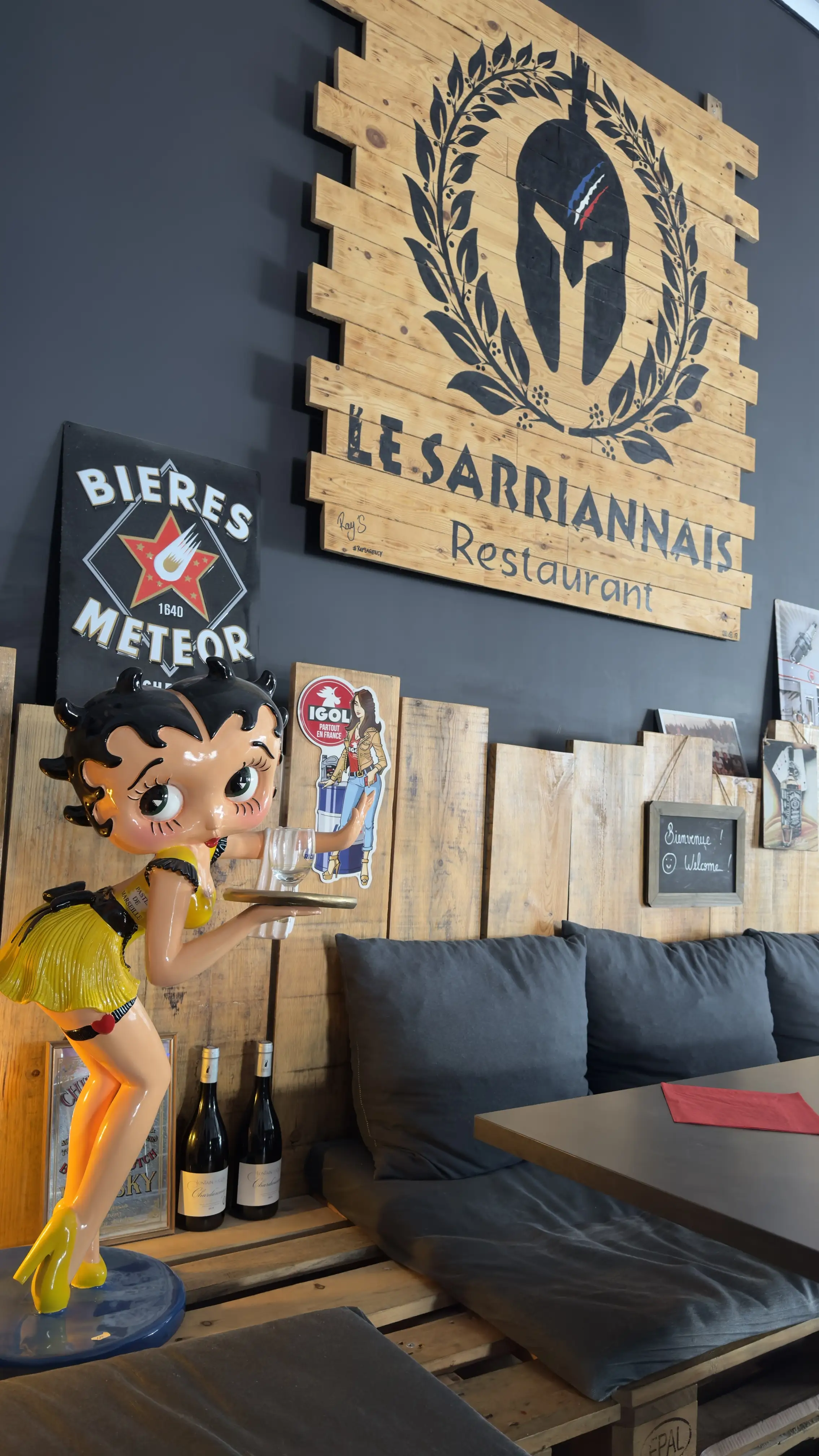L'enseigne en bois du Sarriannais au-dessus des banquettes de la salle
